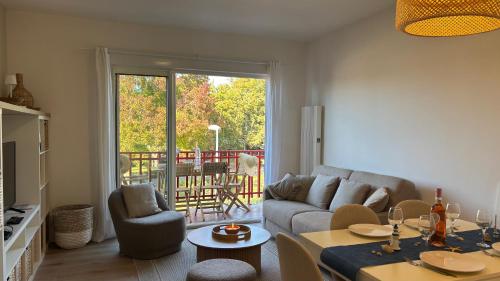 Una sala de estar con un sofá, una mesa y sillas. en T2, 50 m beach, balcony with sea view, en La Teste-de-Buch