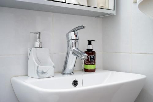 ein Waschbecken mit einem Wasserhahn und einer Flasche Seife in der Unterkunft Family Home, with Sea & Mountain view in Kalamaki