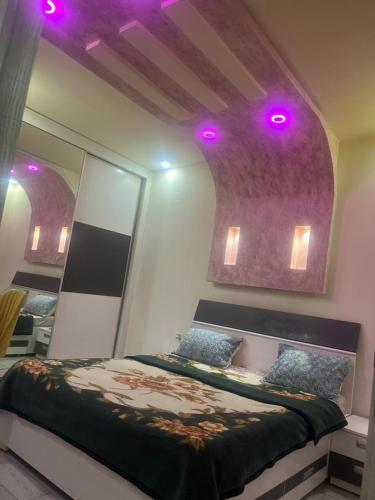 ein Schlafzimmer mit einem Bett mit Spiegel und violetten Lichtern in der Unterkunft Lotiss in Monastir
