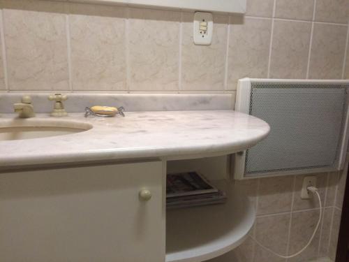 baño con lavabo blanco y ventilador en Apartamento Orsi, en Gramado