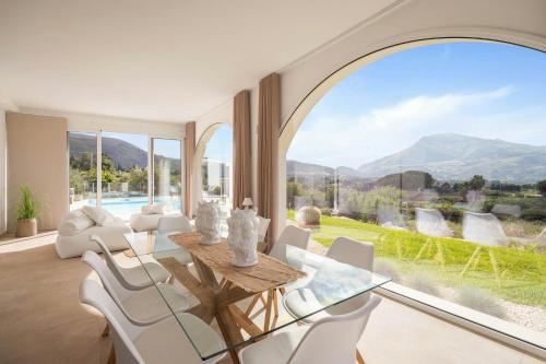 ein Wohnzimmer mit einem Tisch und Stühlen sowie einem großen Fenster in der Unterkunft Historic Villa Overlooking Scopello Sea Stacks in Castellammare del Golfo