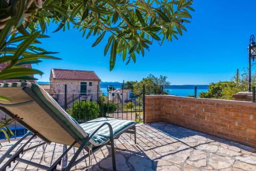 een terras met een stoel en een bakstenen muur bij House Vedrana in Igrane