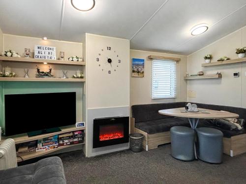 een woonkamer met een tv en een open haard bij Ali B's Craig Tara in Ayr