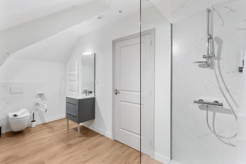 une salle de bain blanche avec une douche et un lavabo dans l'établissement Chambres & sde privatives dans maison partagée, à Clisson