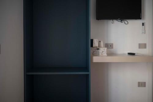 a room with a blue wall with a tv and shelves at Rosa Rooms Pompei in Pompei