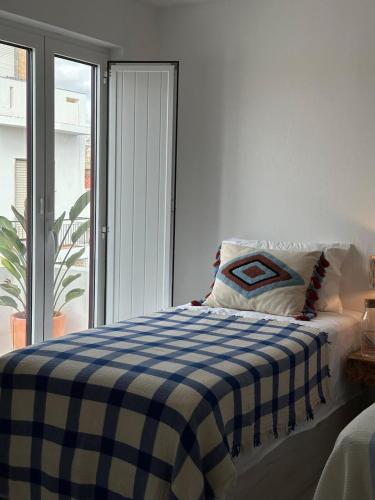 a bed with a blue and white checkered blanket at Casa Dar Alma in Vila Real de Santo António