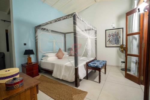 een slaapkamer met een hemelbed en een stoel bij Mannat in Kandy