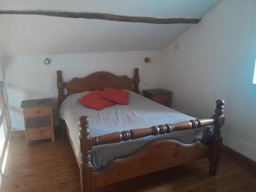 a bedroom with a wooden bed with two red pillows at Gîte des Fraignaies in Saint-Juire-Champgillon