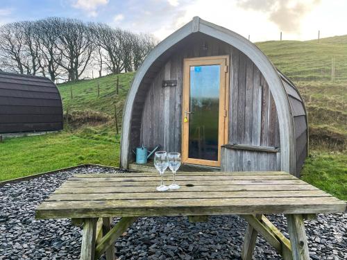 two wine glasses on a wooden table in front of a dome house at Meadow - Uk48483 in Dalton in Furness