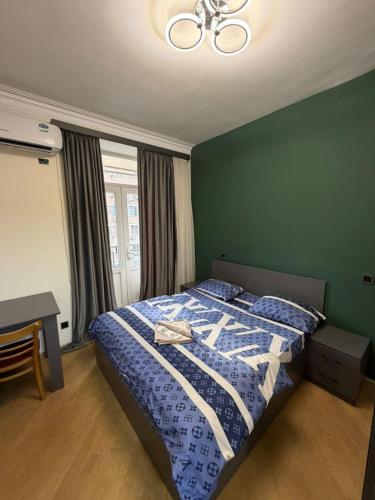 a bedroom with a bed with a blue and white comforter at Guesthouse MA in Yerevan