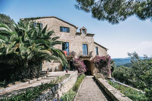 ein großes Steinhaus mit Palmen davor in der Unterkunft Posada del Marqués I A Slow Design Hotel in Esporles