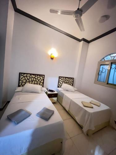 two beds in a room with white walls and windows at Anas Nubian Guest House in Aswan