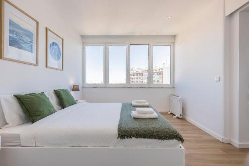 a white bedroom with a large bed with two windows at Eua 112 II in Lisbon