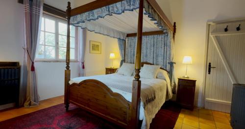 ein Schlafzimmer mit Himmelbett und Fenster in der Unterkunft Le Gîte Pérard in Caylus