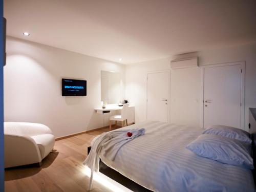 a white bedroom with a bed and a desk at B&B Aquabello in Roeselare