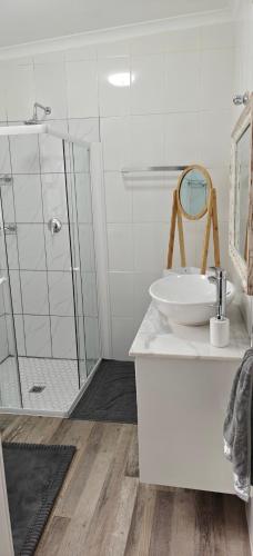 a white bathroom with a sink and a shower at Lagoon Luxury Suites in Walvis Bay