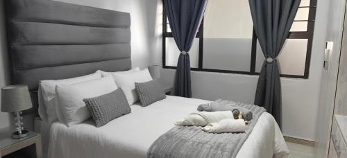 a bedroom with a white bed with two stuffed animals on it at Lagoon Luxury Suites in Walvis Bay