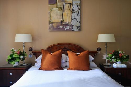 a bedroom with a bed with orange pillows and two lamps at Ettington Park Hotel, Stratford-upon-Avon in Stratford-upon-Avon