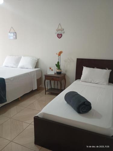 a bedroom with two beds and a table at Pousada Fonte da Samaritana in Vila Velha