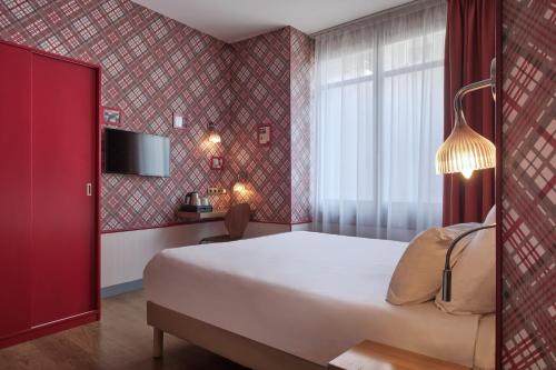 Una habitación de hotel con una cama grande y una ventana. en Hotel Boris V. by Happyculture, en Levallois-Perret