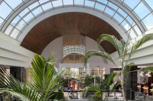 een lobby met palmbomen en een glazen plafond bij Radisson Blu Resort & Spa Cesme in Çeşme