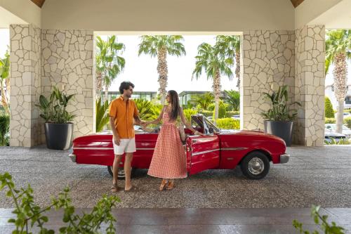 een man en een vrouw die naast een rode auto staan bij Radisson Blu Resort & Spa Cesme in Çeşme