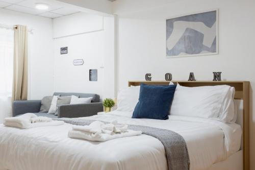 een slaapkamer met een groot wit bed met blauwe accenten bij Cosy Lodge MRT Phra Ram 9 in Bangkok