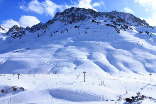 a snow covered mountain with people skiing on a ski slope at Résidence Mer & Golf Tourmalet in La Mongie