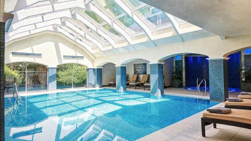a large swimming pool with a skylight in a building at Ettington Park Hotel, Stratford-upon-Avon in Stratford-upon-Avon