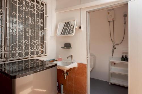 een badkamer met een wastafel en een douche bij Cosy Lodge MRT Phra Ram 9 in Bangkok