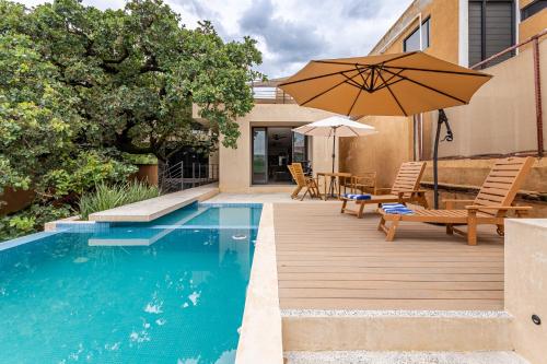 a swimming pool with an umbrella and chairs and a table with an umbrella at Casa Encino - Oasis to share in Tepoztlán