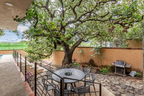 a patio with a table and chairs under a tree at Casa Encino - Oasis to share in Tepoztlán
