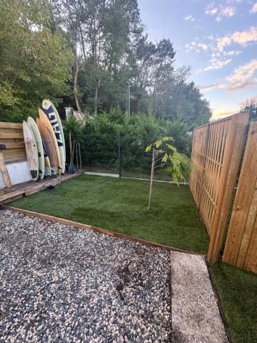 een tuin met surfplanken naast een hek bij L'orangerie in Seignosse