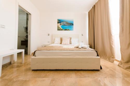 a white bedroom with a large bed and a mirror at Artemar in Porto Cesareo