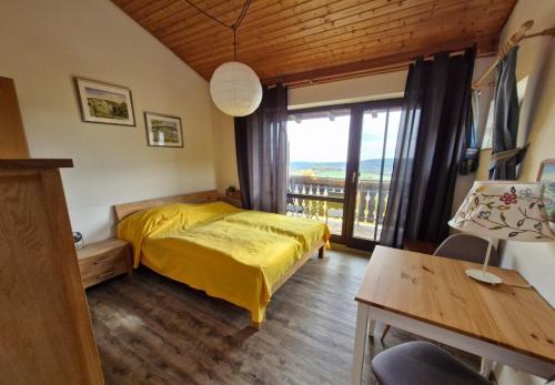 een slaapkamer met een geel bed en een balkon bij Ferienhaus Rhönblick in Bischofsheim an der Rhön