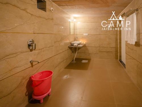 a bathroom with a red trash can and a sink at Camp Inn Jaisalmer Resort in Jaisalmer