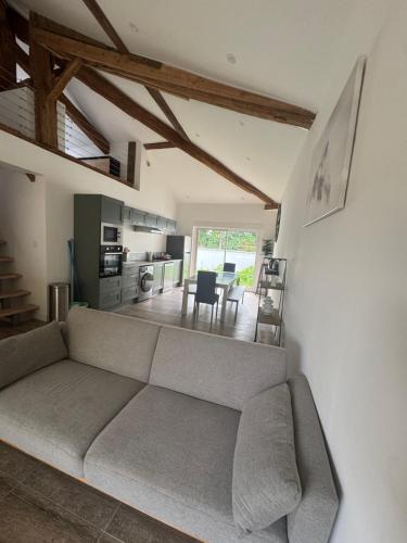 een woonkamer met een bank en een keuken bij L'orangerie in Seignosse