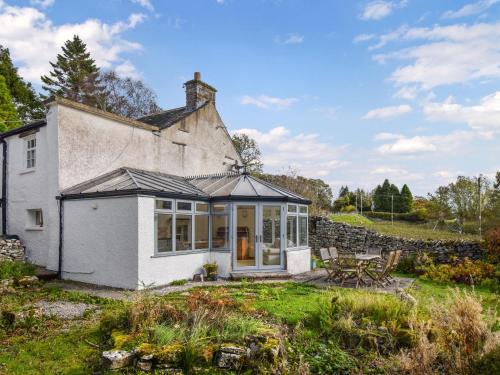 een wit huis met een serre en een tafel bij Low Lane Cottage in Crosby Garrett