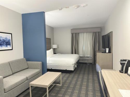 um quarto de hotel com uma cama e um sofá em Merica Inn & Suites em Wills Point
