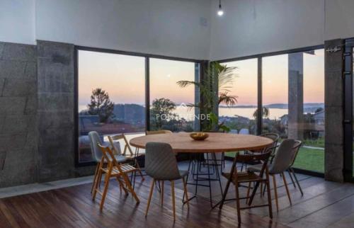 Blackhouse jacuzzi piscina في بونتيفيدرا: غرفة طعام مع طاولة وكراسي خشبية