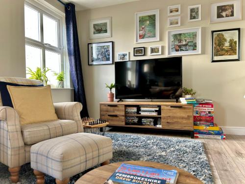 a living room with a flat screen tv and chairs at Charming Pembrokeshire Townhouse in Pembrokeshire