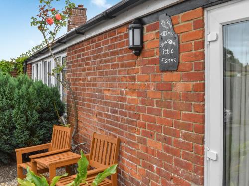 two wooden chairs sitting outside of a brick building at Little Fishes in Ryde