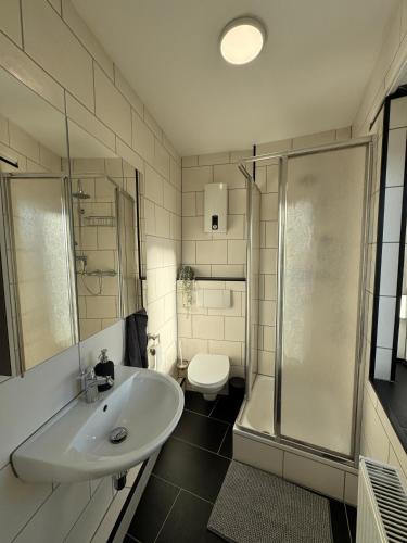 a bathroom with a sink and a shower and a toilet at Schönes Apartment für 5 Personen nahe Zentrum & Borussia Park MG77 in Mönchengladbach