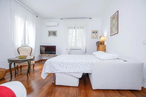 a white bedroom with a bed and a tv at Apartment with Free Parking Easy Access to Venice in Mestre