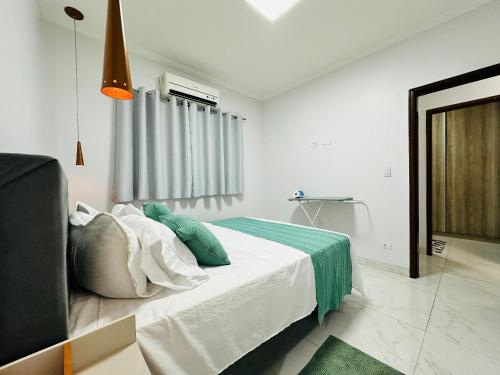 ein weißes Schlafzimmer mit einem Bett mit einer grünen Decke in der Unterkunft Casa c/ Suíte, Ar Cond, Área Gourmet, Bairro Nobre in Ourinhos