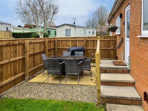 a patio with a table and chairs and a fence at Swaleside Cottage in Topcliffe