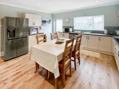 a kitchen with a table and chairs and a refrigerator at Swaleside Cottage in Topcliffe