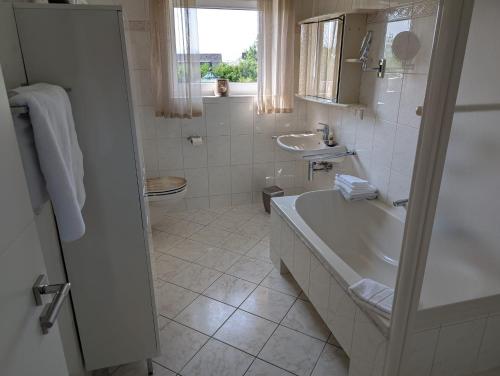 ein weißes Badezimmer mit Badewanne und Waschbecken in der Unterkunft Ferienhaus MAWO 4 Sterne in Andernach