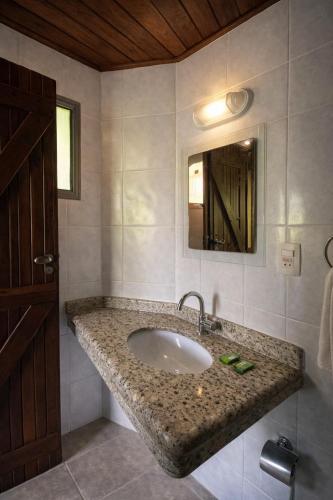 a bathroom with a sink and a mirror at Pousada Nusa Dua Maresias in Maresias