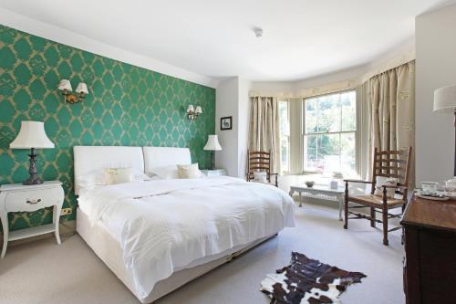 een slaapkamer met een wit bed en een groene muur bij The Plough Inn in Dorking